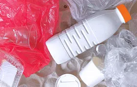 A collection of post-consumer plastic waste, including a white HDPE milk jug, highlighting the importance of recycling for materials like High-Density Polyethylene.