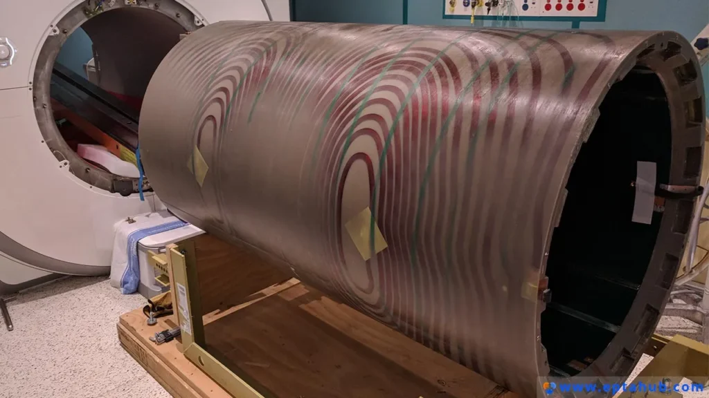 ภาพถ่ายของกระบอกขดลวดไล่ระดับสนามแม่เหล็ก MRI ขนาดใหญ่ แสดงให้เห็นถึงรูปแบบที่ซับซ้อนของขดลวดทองแดงภายใน ซึ่งเป็นตัวอย่างในโลกแห่งความเป็นจริงที่การจัดการกระแสไหลวนในวัสดุตัวนำมีความสำคัญอย่างยิ่งต่อวิศวกรรมอุปกรณ์ทางการแพทย์.