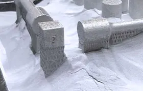 A close-up of several complex parts just after being manufactured with Selective Laser Sintering (SLS), emerging from the unsintered polymer powder bed inside the 3D printer.